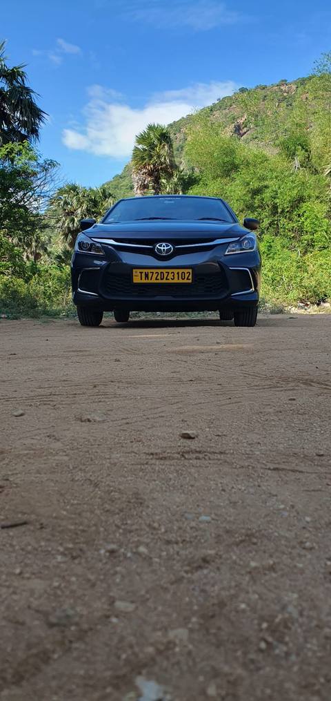 Our grey Toyota Glanza parked in front of green hills